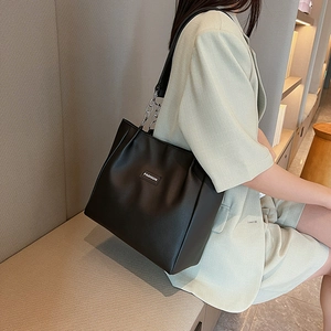 Grand sac cabas noir en cuir avec bandoulière chaîne porté par un mannequin