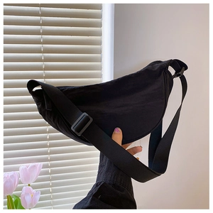 Detail of black nylon dumpling bag featuring wide adjustable strap and zipper closure