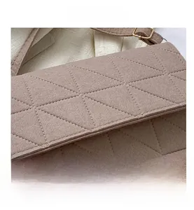 Détail du sac à bandoulière en feutre rose avec matelassage triangle et boucle en métal doré