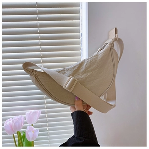 Detail of creamy pleated nylon crescent bag featuring adjustable fabric shoulder strap