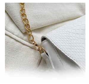 Close-up of white snake texture leather bag with gold metal chain and hook detail