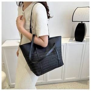 Detail view of black minimalist tote bag with contrast smooth and woven leather textures