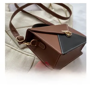 Close-up of contrast stitching and gold metal twist lock on a bicolor crossbody bag