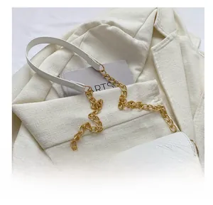 Close-up of white crocodile texture handbag with golden crescent buckle and chain strap