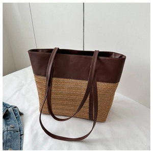 Detail of contrast stitching and texture on brown leather and woven straw tote bag