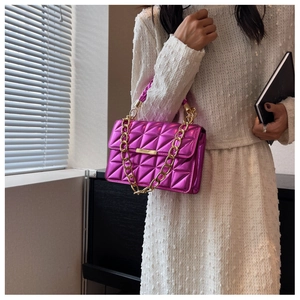 Detail of quilted metallic pink crossbody bag with chunky gold chain strap on model