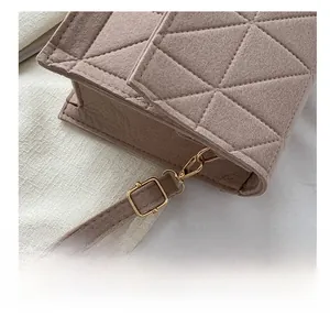 Détail du sac à bandoulière en feutre marron avec motif matelassé et crochets dorés