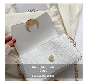 Close-up of white crocodile embossed leather bag with gold magnetic metal clasp