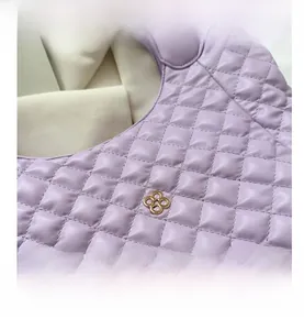 Close-up of purple quilted pattern and gold clover ornament on the crossbody tote bag