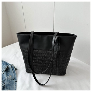Close-up of black tote bag featuring modern leather and woven texture contrast design