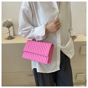 Dettaglio della borsa a tracolla rosa con cuciture diagonali e catena dorata