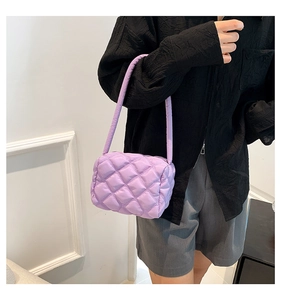 Detailed close-up of purple quilted nylon fabric and puffer texture on a baguette bag