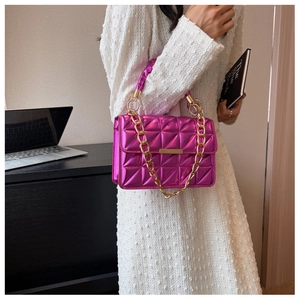 Close-up of metallic magenta quilted handbag with gold chain and clasp detail