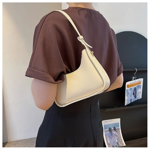 Detailed close-up of cream hobo underarm bag showing smooth leather and golden hardware