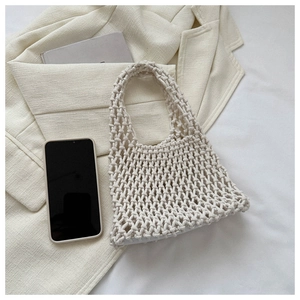 Detail of cream beige hand-woven cotton mesh bag on a stylish beige blazer background