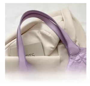 Detail of light purple quilted tote bag showing sturdy reinforced arc handles