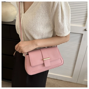 Détail d'un petit sac carré rose clair avec fermoir en métal doré et bandoulière fine