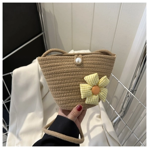 Close-up of hand-woven bucket bag with pearl closure and yellow plaid flower detail