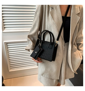 Detail of black crocodile texture tote bag with detachable strap and small envelope charm