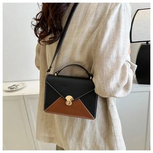 Detail of color-block flap bag featuring a gold metal clasp and white contrast stitching