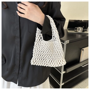 Detail of a handmade cream crochet mesh wrist bag with thick woven cotton rope texture