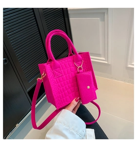 Detailed close-up of rose red felt handbag with crocodile texture and gold hardware