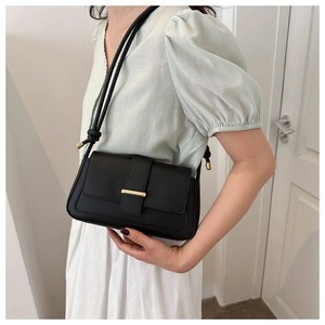 Détail d'un sac à bandoulière noir vintage avec barres dorées et doubles lanières nouées