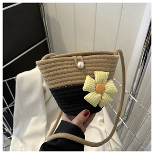 Detail of hand-woven straw bucket bag featuring a yellow gingham flower and pearl charm