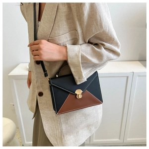 Close-up of dual-tone envelope crossbody bag with gold twist lock and contrast stitching