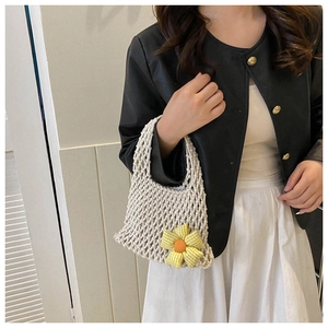 Detailed close-up of handmade hollow knit wrist bag with a yellow plaid floral ornament
