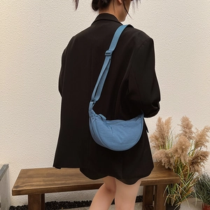 Blue nylon half-moon crossbody bag with adjustable strap worn by model in casual scene
