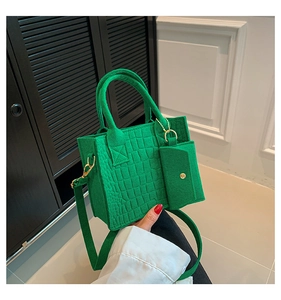 Detail of green crocodile embossed felt tote bag with matching charm and shoulder strap