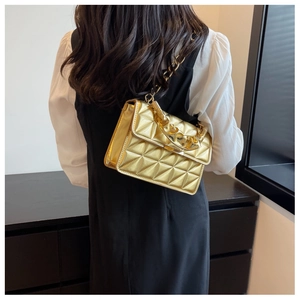 Quilted gold shoulder bag with chain strap and pleated handle shown on model outfit