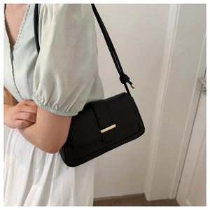 Sac à bandoulière rectangulaire noir avec fermoir doré et sangle nouée sur mannequin