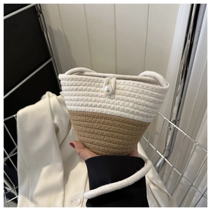 Close-up of woven bucket bag featuring pearl closure and bicolor knit texture