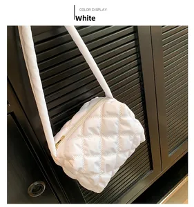 Detail of white quilted nylon shoulder bag featuring puffy diamond texture and zipper