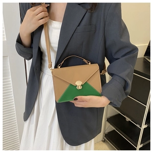 Detail of a two-tone envelope bag in camel and green with a golden twist-lock closure