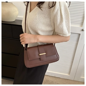 Détail d'un sac bandoulière en cuir marron foncé avec une élégante boucle en métal doré chic
