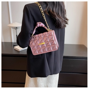 Detail of metallic purple quilted handbag featuring a chunky gold chain and pleated handle