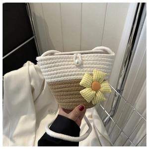 Detail of two-tone woven bucket bag with sunflower fabric charm and pearl snap button