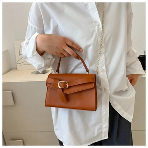 Detail of caramel leather handbag with gold chain strap and textured flap closure