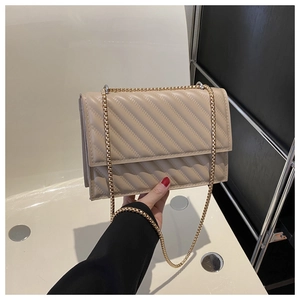 Dettaglio di una borsa a tracolla trapuntata color tè al latte con catena dorata