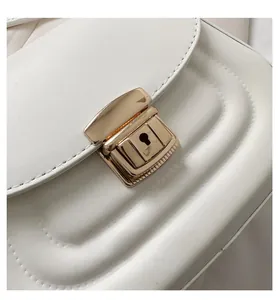 Detail of white leather crossbody bag with quilted texture and golden metal buckle