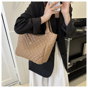 Quilted beige tote bag detail showing large capacity design and golden flower logo