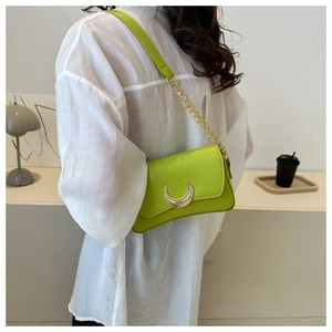 Detail of lime green faux crocodile leather handbag with crescent gold buckle and chain