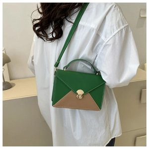 Detail of green and tan patchwork leather handbag with gold twist lock and handle
