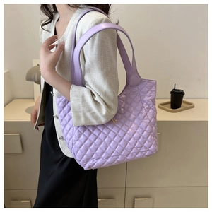 Detail of light purple quilted tote bag with gold metal logo and long shoulder handles