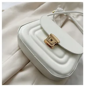 Detail of white quilted crossbody bag with luxury gold square clasp and wave texture