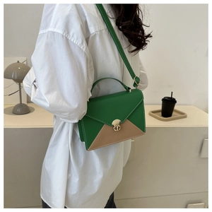 Detail of green and khaki patchwork shoulder bag with gold twist lock on white shirt