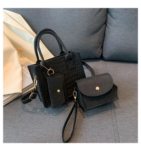 Detailed set of black quilted felt handbags including tote and pouches on a soft sofa
